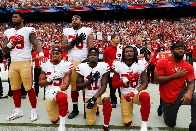 Member of the San Francisco 49ers kneel and stand during the playing of the National Anthem before an NFL football game against the Washington Redskins in Landover, Md., Sunday, Oct. 15, 2017. Kneeling are (L-R) strong safety Eric Reid (35), wide receiver Marquise Goodwin (11) and defensive back Adrian Colbert (38). (AP Photo/Alex Brandon)