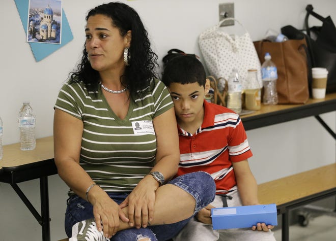 In this Tuesday, Nov. 14, 2017, photo, recent transplant from Puerto Rico, Arieliss Valencia sits next to her son Anthony, right, a fifth grader at Riverdale Elementary School after school supplies were handed out to the students in Orlando, Fla. Anthony left Puerto Rico with his family for central Florida after Hurricane Maria destroyed his home. He is living with relatives and has been welcomed into Orlando's Riverdale Elementary School. (AP Photo/John Raoux)