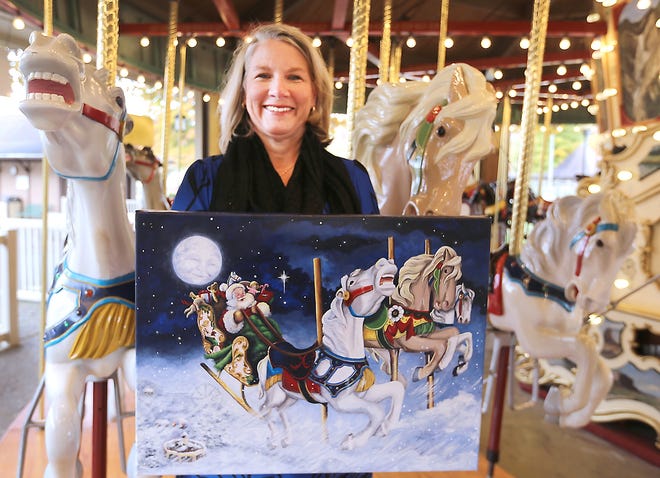 Christy Bloom displays her painting of the carousel at Tuscora Park. (TimesReporter.com / Jim Cummings)