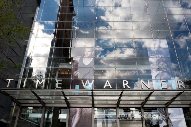 In this Oct. 24, 2016, file photo, clouds are reflected in the glass facade of the Time Warner building in New York. The Justice Department intends to sue AT&T to stop its $85 billion purchase of Time Warner, according to a person familiar with the matter who was not authorized to discuss the suit ahead of its official filing. (AP Photo/Mark Lennihan, File)