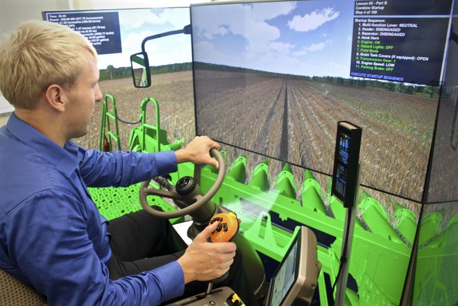 In this Tuesday, Oct. 17, photo, Nick Schiltz, agricultural sciences instructor at Riverland Community College, demonstrates how he uses the new combine simulator for training students on operating farm equipment at the community college in Austin, Minnesota. "This is very similar, or very close to the real thing," Schiltz said while using the simulator. "We have some tremendous training opportunity here (for students)." (Hannah Yang/The Rochester Post-Bulletin via AP)