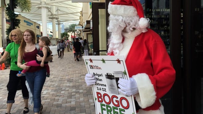 A santa outside Parfum Europa tries to attract last minute shoppers on Christmas Eve at Palm Beach Outlets in West Palm Beach, December 24, 2015. (Greg Lovett / The Palm Beach Post)
