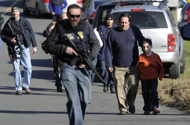 FILE PHOTO: Parents leave a staging area after being reunited with their children following a shooting at the Sandy Hook Elementary School in Newtown, Conn. where authorities say a gunman opened fire, leaving 27 people dead, including 20 children, Friday, Dec. 14, 2012.