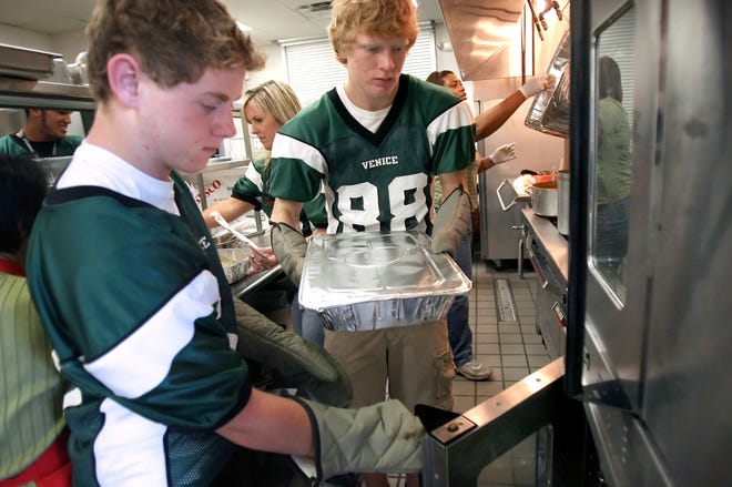 Venice High football players Isaac Carpenter, left, and David Voigt, right, pull out trays of mashed potatoes as they volunteer to feed the needy Thanksgiving meals at The Salvation Army in Venice in 2009. The Indians volunteer their time every Thanksgiving as a way of giving back to their community. [HEARLD-TRIBUNE STAFF FILE PHOTO / CHIP LITHERLAND]
