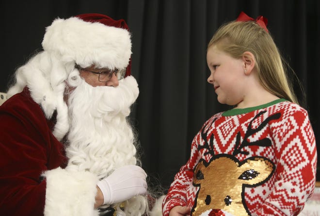 Kendall Thomas, 7, sits on Santa Claus's lap as she tells him what she would like for Christmas during the opening of the 2017 Tinsel Trail at the Tuscaloosa River Market on Monday. [Staff Photo/Erin Nelson]