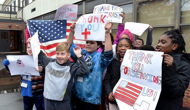 Fifth-graders at the Gertrude C. Folwell Elementary School in Mount Holly hold up signs and the American flag as they salute veterans during the school's annual Turkey Trot 1-mile walk on Wednesday, Nov. 22, 2017. [NANCY ROKOS / STAFF PHOTOJOURNALIST]