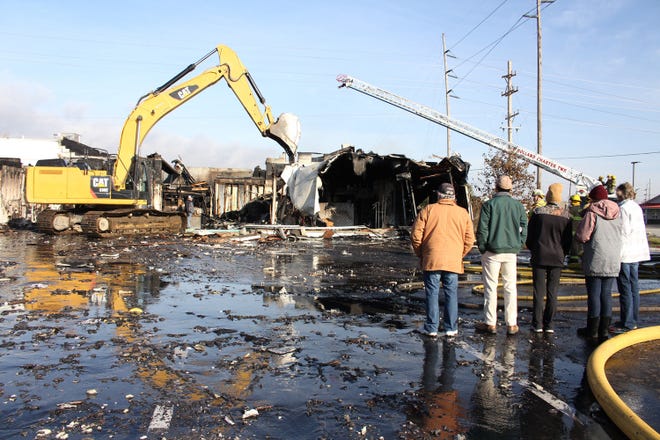Employees look on as Graphix Signs & Embroidery is torn down by Holland Township firefighters on Monday, Nov. 20. Nobody was injured in the fire, which started just before 3 a.m. [Sentinel File]