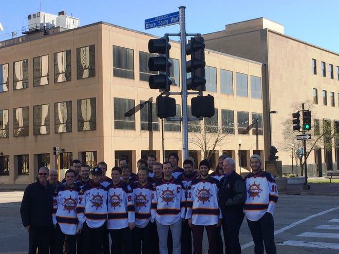 DAVE EMINIAN/JOURNAL STAR Peoria Rivermen players, plus family members of Bruce Saurs, gather in front of the street sign unveiled in honor of the late longtime team owner in a ceremony Saturday in downtown Peoria.
