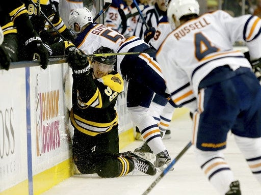 Bruins center Tim Schaller (left) hits the ice as he is checked along the bench by Edmonton Oilers left wing Anton Slepyshev (58) during Boston's 4-2 loss to Edmonton on Sunday. [AP Photo/Mary Schwalm]