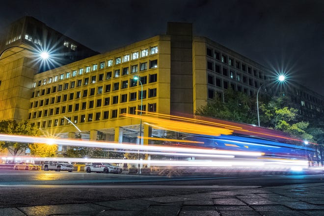 Traffic along Pennsylvania Avenue in Washington streaks past the Federal Bureau of Investigation headquarters building Wednesday night, Nov. 1, 2017. Scores of U.S. diplomatic, military and government figures were not told about attempts to hack into their emails even though the FBI knew they were in the KremlinþÄôs crosshairs, The Associated Press has learned. (AP Photo/J. David Ake)