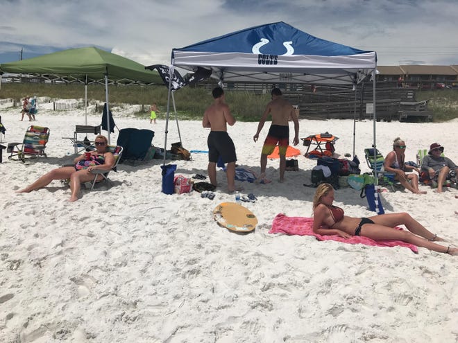 People sit beneath beach tents in Walton County. Restrictions on the placement of beach tents are among topics at a Dec. 12 public hearing. A ban on tents larger than 10 by 10 feet failed after public outcry in Panama City Beach in 2016. [DAILY NEWS FILE PHOTO]