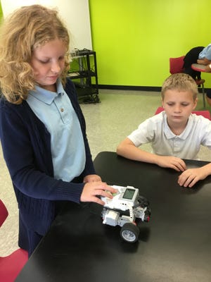 Rachel Reddy, 10, programs a robot while classmate Elijah Brock, 10, looks on during a robotics demonstration conducted by the Tampa Museum of Science & Industry on Monday at Combee Academy of Design & Engineering in Lakeland. [ ERIC PERA/THE LEDGER ]