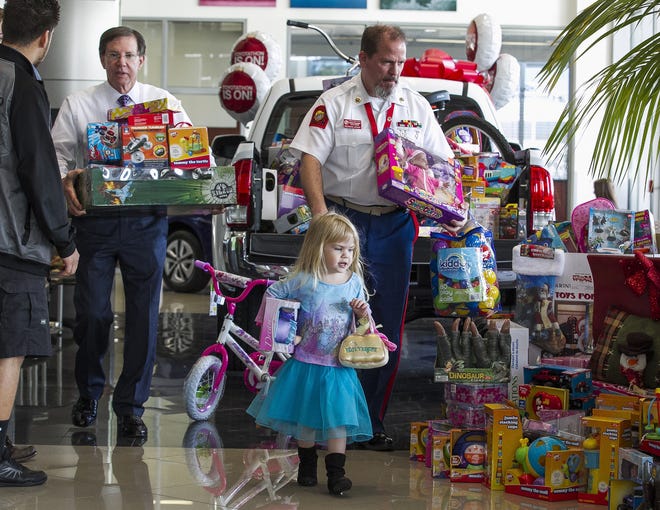 During last year's Toys For Tots drive, Patrick Joynt, a disabled Marine, right, got some help from Frank DeLuca, left, owner of DeLuca Toyota, as they loaded up donated toys, with Joynt's 3-year-old daughter Abbie pitching in. This year's drive is underway and donations are being sought. [Doug Engle/Staff photographer/file]
