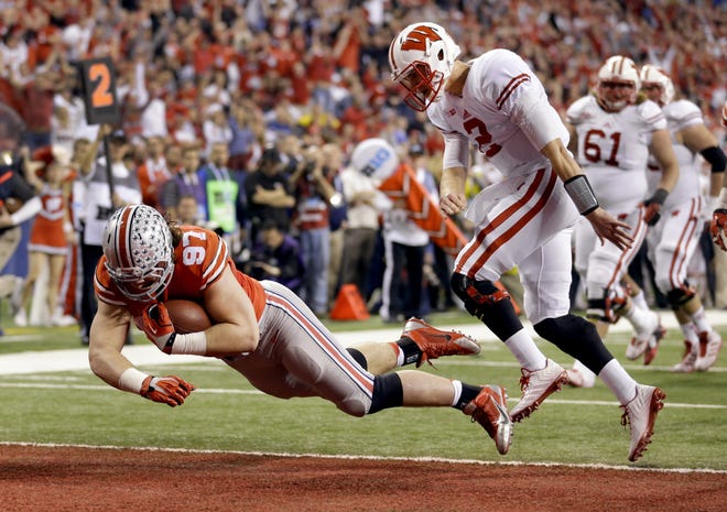 In this Dec. 6, 2014, file photo, Ohio State defensive lineman Joey Bosa, left, falls into the end zone after recovering a fumble and running it back for a touchdown against Wisconsin during the Big Ten championship game. [AP Photo/Michael Conroy, File]