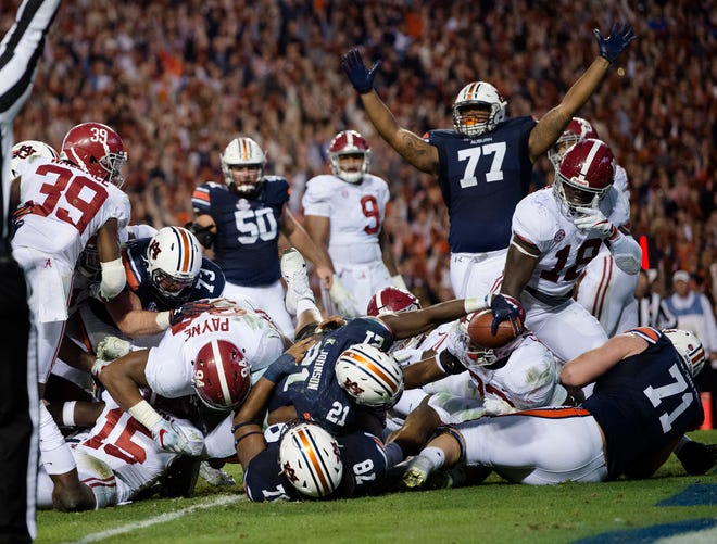 Auburn running back Kerryon Johnson (21) reaches over the goal line for the go-ahead touchdown against Alabama during the Iron Bowl on Saturday in Auburn, Ala. Auburn won, 26-14, to earn a spot in this Saturday's SEC title game. [Albert Cesare/The Montgomery Advertiser via AP]