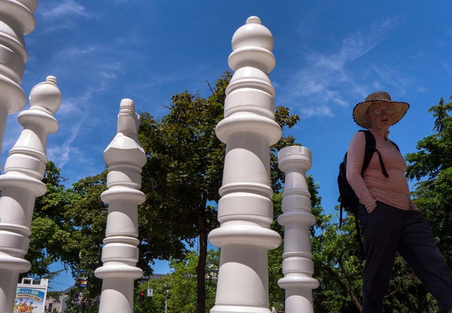 A pedestrian passes by giant chess pieces arranged on a chessboard at the Park Blocks in downtown Friday afternoon, part of a continuing initiative by the city of Eugene to encourage people to enjoy downtown and urban parks throughout the summer months. (Brian Davies/The Register-Guard)