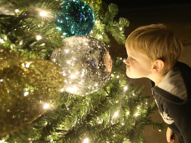 Caleb Duty,4, checks out his reflection in an ornament. Hundreds attended the 38th annual Christmas Festival and Tree Lighting on Monday at Aaron Bessant Park. Go to newsherald.com for a related gallery and 360 video. [PATTI BLAKE/THE NEWS HERALD]