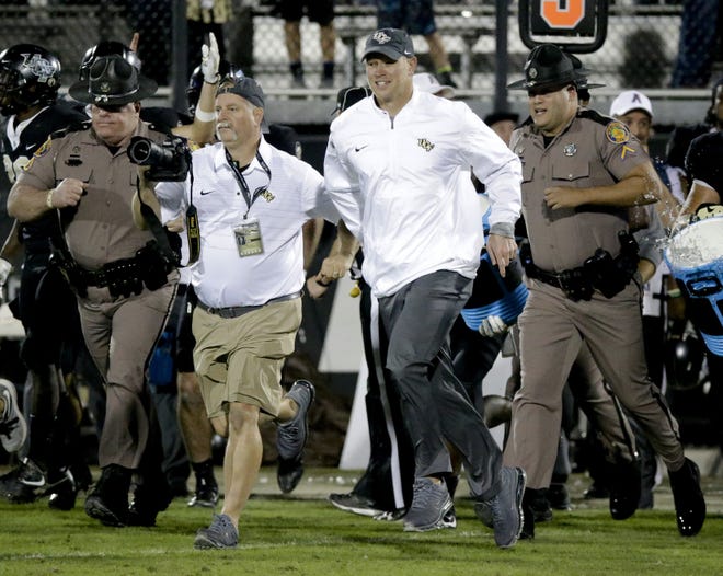 Central Florida coach Scott Frost, center, runs onto the field after the team defeated South Florida 49-42 Friday in Orlando. [AP Photo / John Raoux]