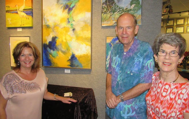 Marna Conner, owner of Picture Perfect Frame & Gallery in Palm Coast, talks with guests Arvid and Pat Olson about the current featured artist's work in the "Birds and Paradise" show during an opening reception Nov. 16. [News-Tribune/Danielle Anderson]