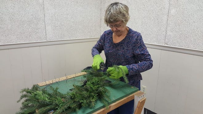 Volunteer Marilyn Zak inserts greens into a metal base to create a fresh pine wreath for the annual Waynesboro Hospital Auxiliary greens, bake and craft sale Tuesday morning at the Rouzerville Community Center.