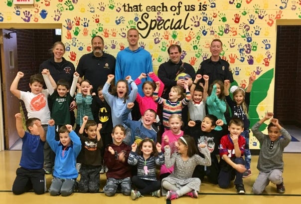 Students at the Assawompset Elementary School in Lakeville, seen here with local firefighters, have endeavored to get engaged in the community this school year. Just recently, students have honored local veterans, hosted a senior breakfast and met with local firefighters and police to learn about safety. [Submitted]