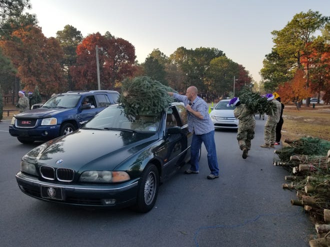 Fort Bragg soldiers tie Christmas trees atop cars as part of the Trees for Troops giveaway at the Smith Lake Recreation Area on Friday, Dec. 1. [Drew Brooks/The Fayetteville Observer]