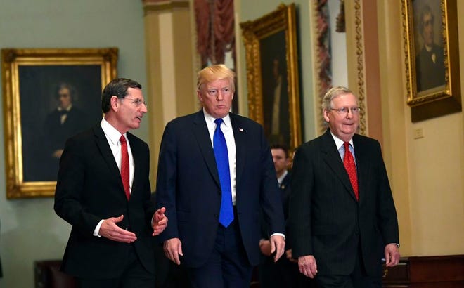President Donald Trump, center, walks with Sen. John Barrasso, R-Wyo., left, and Senate Majority Leader Mitch McConnell of Ky., right, as he arrives on Capitol Hill in Washington.
