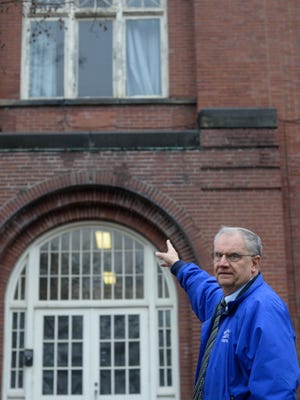 Ravenna director of business operations Bill Wisniewski points toward the principal's office atop the the the old school building on the corner of Walnut Street and Highland Avenue in Ravenna.