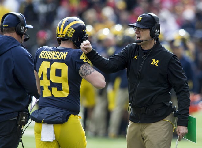 Michigan head coach Jim Harbaugh, right, congratulates long snapper Andrew Robinson (49) after a Michigan touchdown in the first quarter of an NCAA college football game against Ohio State in Ann Arbor, Mich., Saturday, Nov. 25, 2017. (AP Photo/Tony Ding)