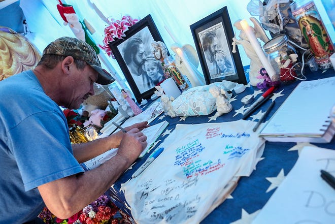 Douglas Pimm signs a memorial book of his great-niece, Mariah Woods, 3, at a memorial site along Dawson Cabin Road at the intersection of Ernest King Road in Jacksonville, Wednesday morning. Pimm traveled from Mount Morris, New York. Visitation for Mariah Woods is being held Wednesday from 4 to 6 p.m. at Jones Funeral Home, Jacksonville. [John Althouse / The Daily News]
