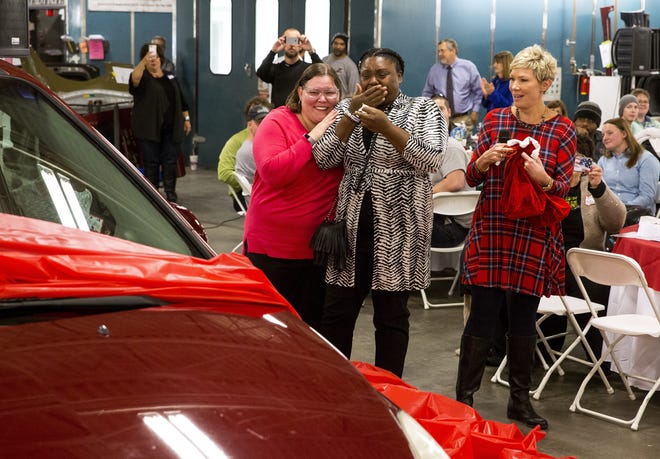 A new car for Alana Yates, center, is unwrapped at Zara's Collision Center on Wednesday during the business' holiday car giveaway luncheon event. With Yates is her friend, Dawn Scheller, left, and Julie Zara. [Rich Saal/The State Journal-Register]
