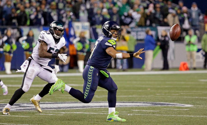 Seattle Seahawks quarterback Russell Wilson, right, shovels the ball on the run as Philadelphia Eagles’ Nigel Bradham moves in during the second half of an NFL football game Sunday, Dec. 3, 2017, in Seattle. (AP Photo/Ted S. Warren)