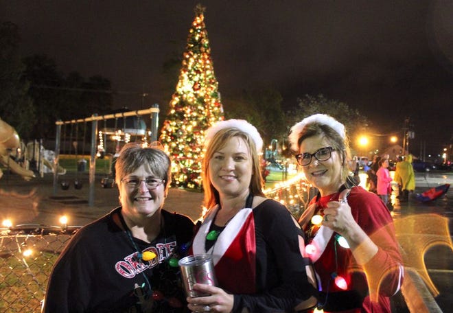 Gonzales Administrative Secretary Lisa Babin (left) poses in front the city Xmas tree with two of Santa's helpers.