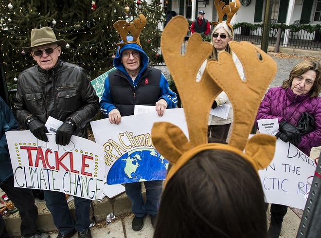 Local residents gather at Main and Court Streets Friday, Dec. 8, 2017, in Borough Doylestown with members of PennEnvironment during a "caribou caroling" protest to express the possibility of opening of the Arctic National Wildlife Refuge in Alaska to oil and gas drilling, which is included in the Senate tax bill. More than a dozen protestors wearing caribou antlers sang different takes on holiday classics like "Climate Change is Coming to Town" and others. The group will call on U.S. Rep. Brian Fitzpatrick to vote against any tax that includes drilling. [Rick Kintzel / Photojournalist]