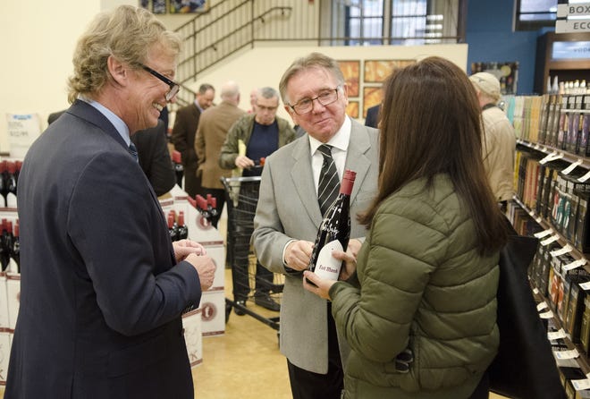 TV show creators/producers Nigel Lythgoe , left, and Ken Warwick speak with Newtown Township resident Lucia Adams after signing a bottle of their Fat Monk wine during the grand opening of a Fine Wine & Good Spirits Premium Collection Store Thursday, Dec. 7, 2017 in Newtown Borough. [BILL FRASER / STAFF PHOTOJOURNALIST]