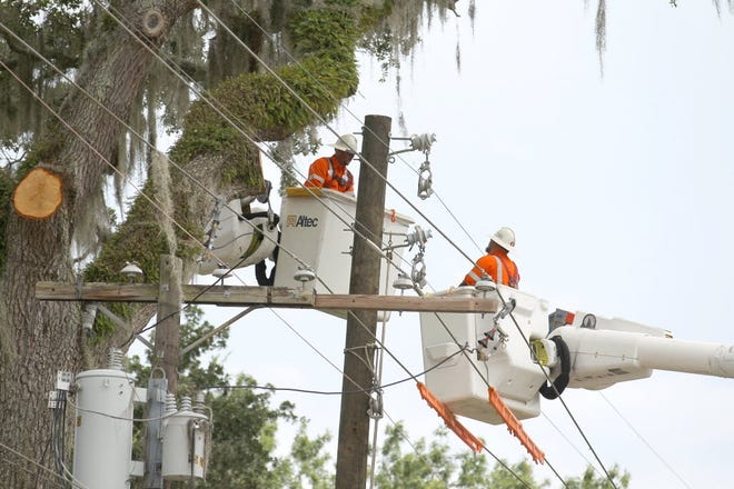 Utility workers put up new poles and lines. [File photo]