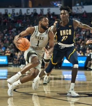 Wake Forest's Keyshawn Woods, left, drives the lane for a basket past UNC-Greensboro's James Dickey during an NCAA college basketball game, Friday, Nov. 24, 2017, at Joel Coliseum in Winston-Salem, N.C. (Walt Unks/Winston-Salem Journal via AP)