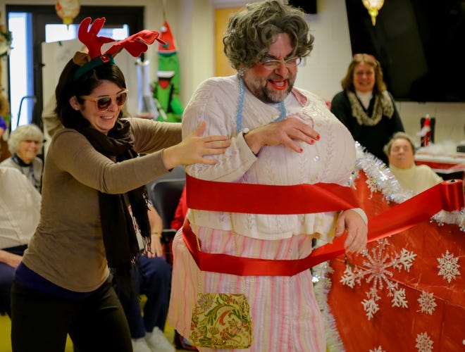 Jessica Cobb, left, wraps Christmas ribbon around Ray Bower, administrator at Riverside Rest Home, as he's dressed up as "Grandma Got Run Over by a Reindeer" last year in Dover. Bower will be participating in another performance next week to raise money for Riverside's Fondest Wish fund. [Shawn St. Hilaire/Fosters.com file]