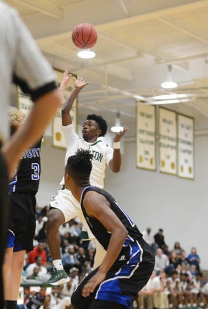 Kinston's Taji Moore (5) scores over Wilson Hunt in the first quarter of a game earlier this season. [Janet S. Carter / The Free Press]
