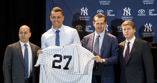 The newest Yankee, Giancarlo Stanton, center, and his new manager Aaron Boone, right middle, are introduced by GM Brian Cashman, left, and owner Hal Steinbrenner, right, during a press conference at baseball's winter meetings in Orlando, Fla., on Monday.