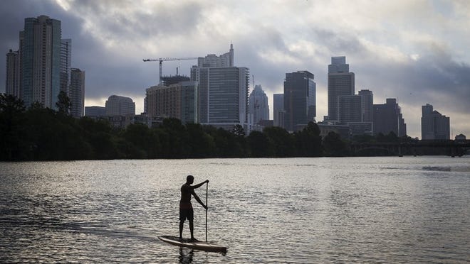 Tony Smith, the owner of Jarvis Boards, looks back at the city skyline while paddle boarding on Lady Bird Lake in Austin, Texas, on Wednesday, July 26, 2017. Jarvis Boards specializes in handmade wooden paddleboards and ships its product around the globe. NICK WAGNER/AMERICAN-STATESMAN