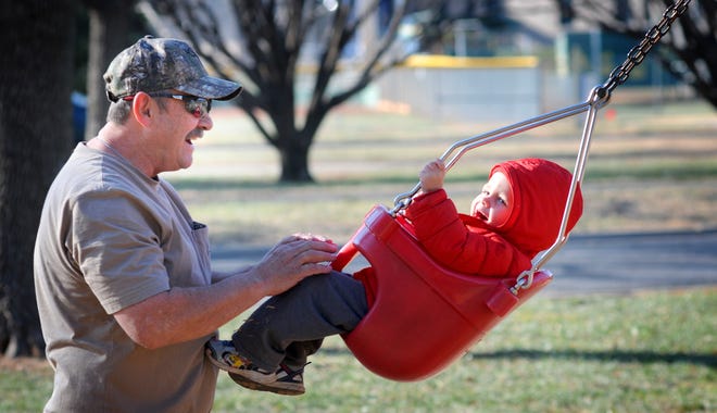 Allen Williams (left) swings his grandson, Liam Hale, 2, Wednesday afternoon in Jerry Ivey Park. Williams said they were enjoying the park. "It's a nice day, but it's going to turn chilly," he said. [TOM DORSEY / SALINA JOURNAL]