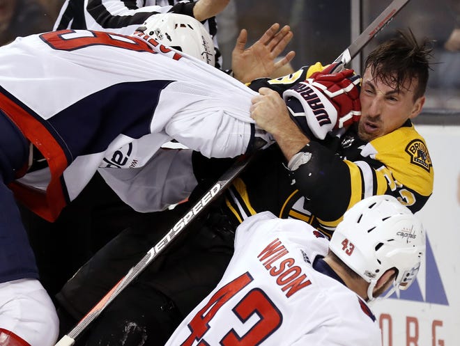 Boston's Brad Marchand is knocked helmet-less to the ice by Washington's Dmitry Orlov during the second period of Thursday's game in Boston. [Winslow Townson/AP]