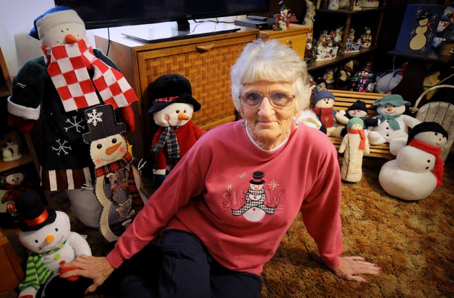 Judy Fisk sits with some of the nearly 600 snowmen she displays in her home each year during the holiday season. [TOM DORSEY / SALINA JOURNAL]