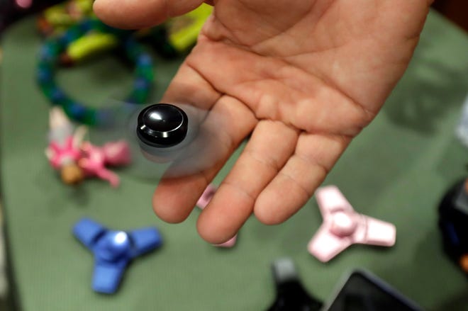 Funky Monkey Toys store owner Tom Jones plays with a fidget spinner in Oxford, Mich. Fidget spinners were among the most searched topics on Google in 2017. [CARLOS OSORIO/AP]
