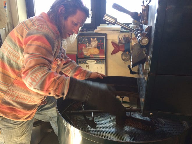 Coastal Roasters owner Donald Machado wears a heat proof glove to move the freshly roasted beans. [Herald News photo by Deborah Allard]