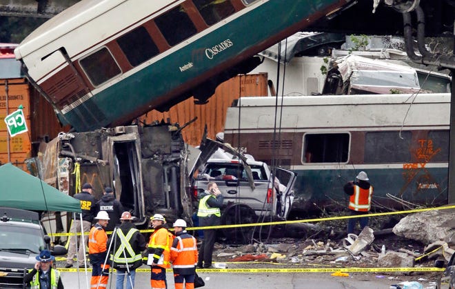 Cars from an Amtrak train that derailed above lay spilled onto Interstate 5 alongside smashed vehicles Monday, Dec. 18, 2017, in DuPont, Wash. The Amtrak train making the first-ever run along a faster new route hurtled off the overpass Monday near Tacoma and spilled some of its cars onto the highway below, killing some people, authorities said. (AP Photo/Elaine Thompson)