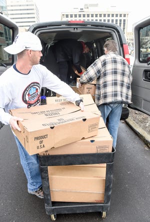 Gary Tallman, a volunteer from the Refuge of Hope Ministries, loads holiday turkeys and hams into a van in Canton. The turkeys and hams were donated by Buckeye Health Plan. (CantonRep.com / Michael Balash)