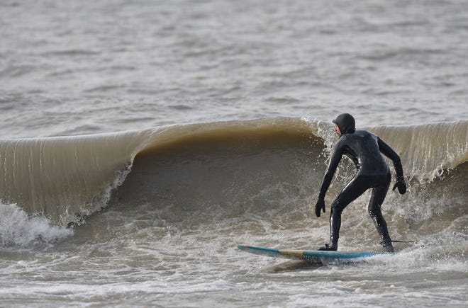 Dan McDavitt surfs at Beach 1 at Presque Isle State Park on Tuesday. With air temperatures in the high 40s and winds from the west at about 20 mph, McDavitt, 37, of Ellwood City, Lawrence County, said the conditions were good for surfing on Lake Erie. [CHRISTOPHER MILLETTE/ERIE TIMES-NEWS]