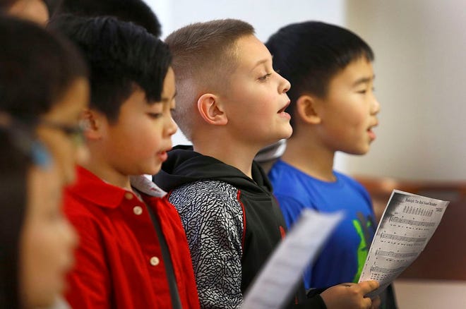 Fourth graders Noah Kilroy, second from right, and Jake Basan, far right, and other members of the Clifford Marshall School 4th grade chorus sing holiday classics to seniors at 100 Southern Artery in Quincy.